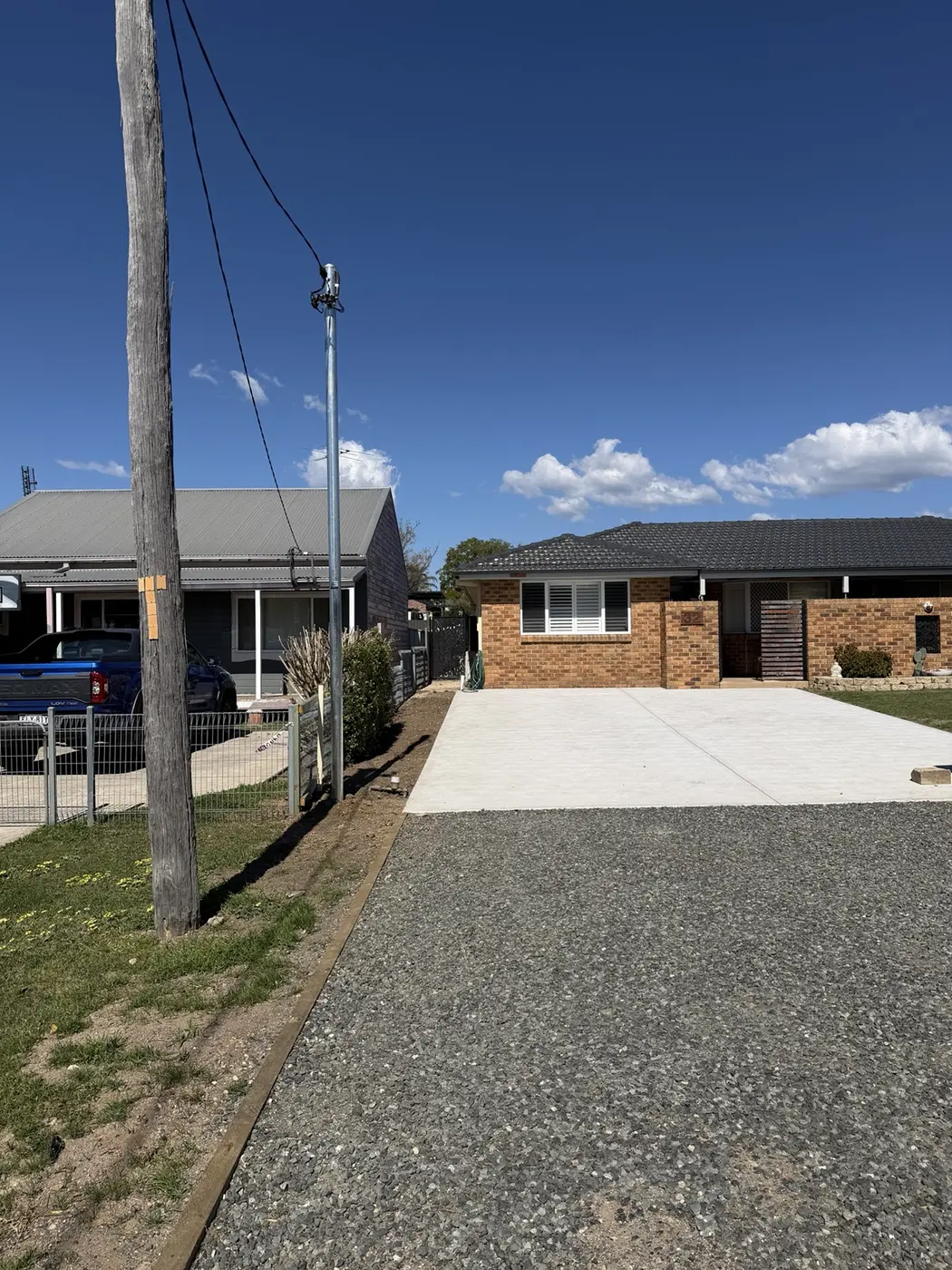 New private power pole installed beside a residential driveway